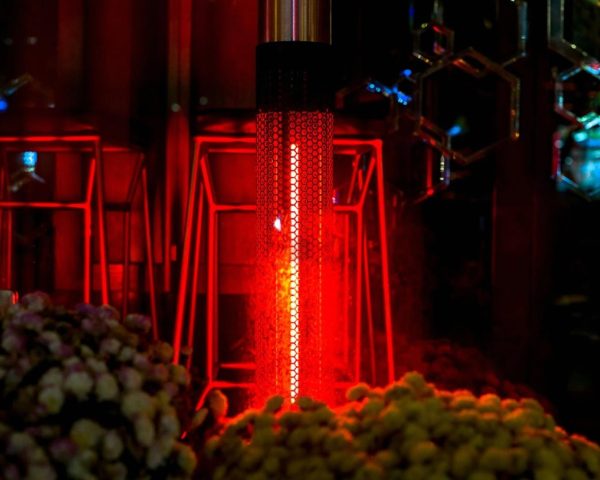 Tall red patio heater glowing beside bar stools and floral arrangements at an outdoor event
